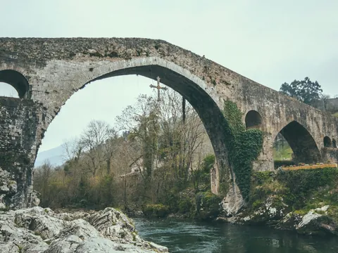 Puente Romano de Cangas de Onís en Asturias, con la emblemática Cruz de la Victoria colgando sobre el río Sella.