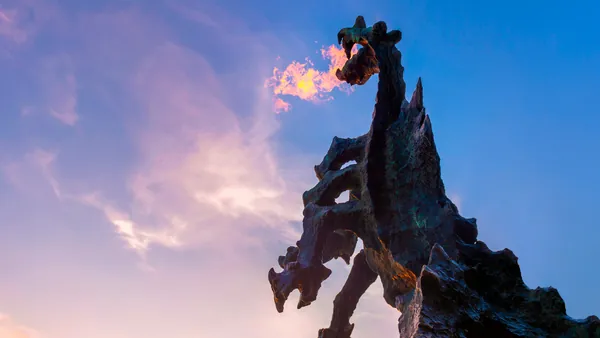 Escultura del dragón de Wawel lanzando fuego al atardecer en Cracovia, Polonia
