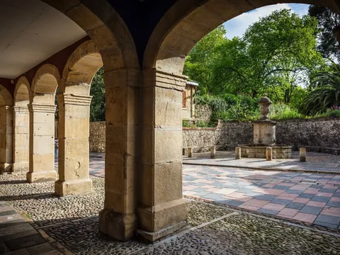 Arcos de piedra en la Plaza de Camposagrado, casco antiguo de Avilés, Asturias, con fuente y jardín