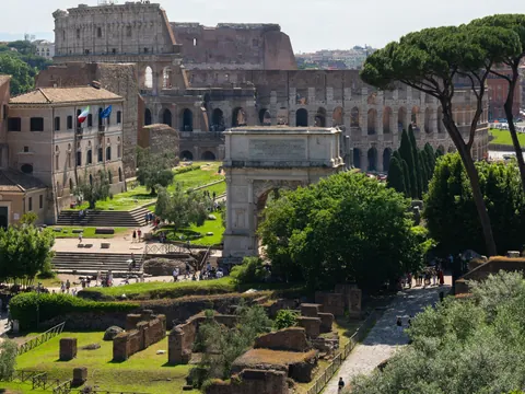 Vista del Coliseo y el Arco de Constantino desde el Foro Romano, rodeados de vegetación.