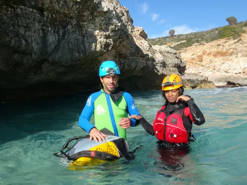 Aventureros con el traje de neopreno y el casco, incluidos en esta actividad de espeleología.