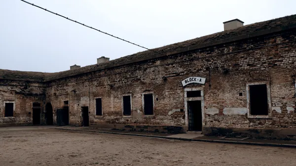 Patio de tierra con un edificio de ladrillo que dice BLOCK A en Terezín.