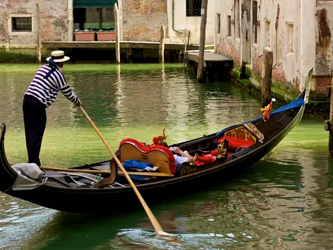 Góndola navegando por los canales de Venecia con gondolero guiando el paseo