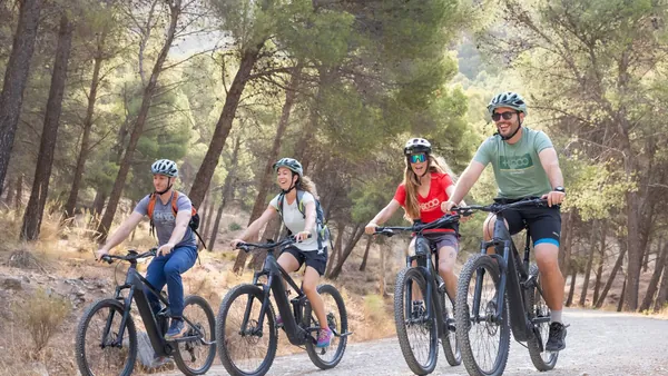 Grupo de ciclistas en e-bikes recorriendo un sendero forestal en El Chorro