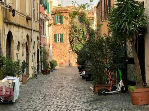 Calle empedrada de Trastevere en Roma con plantas y fachadas antiguas