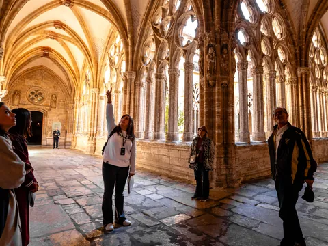 Turistas con guía de buendía observando los arcos góticos del claustro de la Catedral de Oviedo.