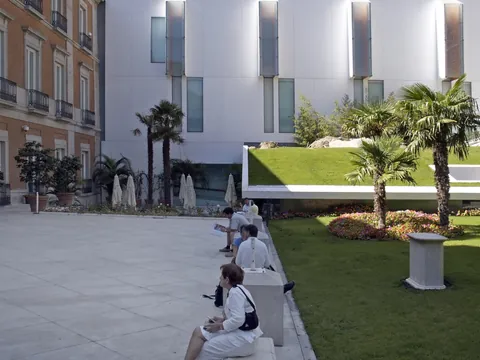 Edificio del Museo Thyssen con gente descansando en bancos.