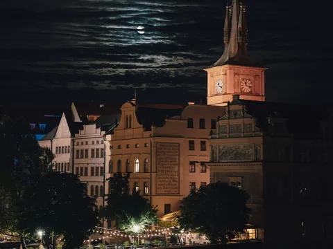 Vista nocturna de edificios históricos bajo la luna en Praga, República Checa