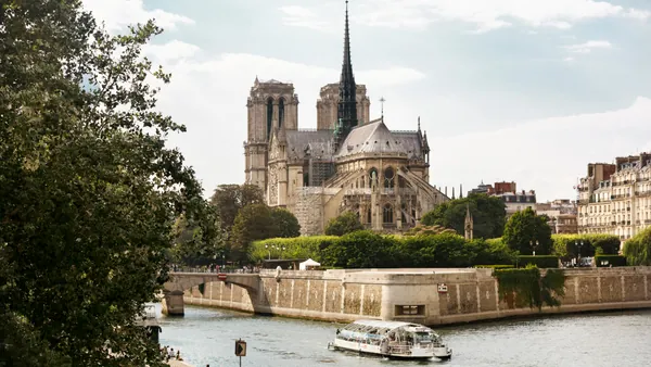 Un bote se desplaza por el río junto al imponente edificio de Notre Dame.