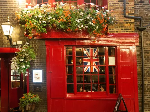 Fachada de un pub tradicional con flores y la bandera británica en Londres.