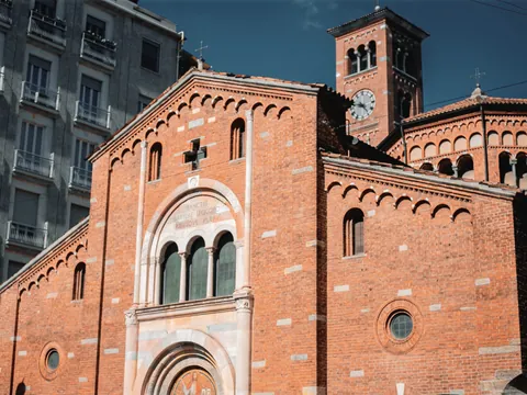 Fachada de la Basílica di San Babila en Milán con ladrillo rojo y campanario