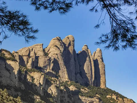 Formaciones rocosas puntiagudas y verticales de la montaña de Montserrat, Barcelona, con cielo azul en un día soleado.