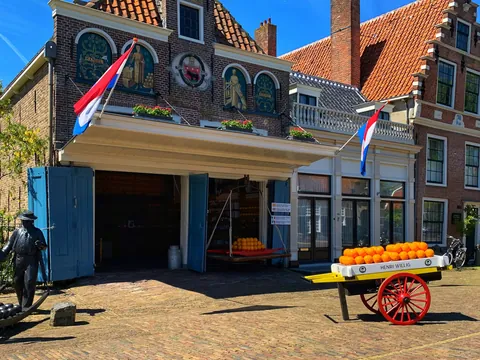 Entrada del mercado de quesos de Volendam con carro y estatuas típicas.