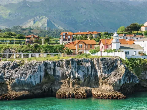 Acantilados de Llanes con casas rurales frente al mar y montañas de Asturias