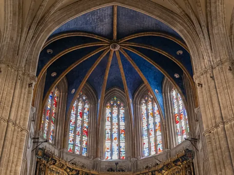 Interior de la Catedral de Oviedo, con su impresionante bóveda azul estrellada y vidrieras góticas llenas de color.
