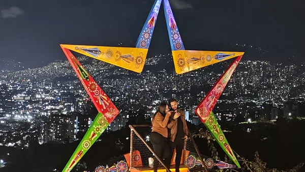 Pareja se realiza una fotografía en uno de los miradores de Medellín con un marco de colores.