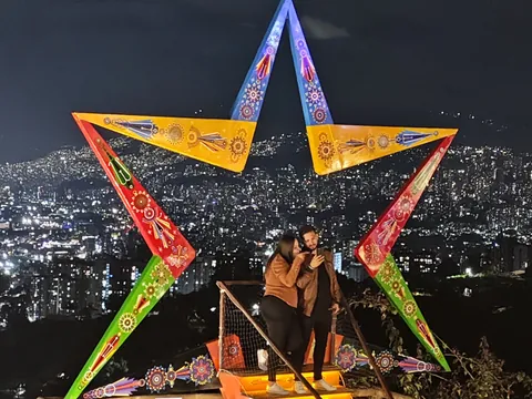 Pareja se realiza una fotografía en uno de los miradores de Medellín con un marco de colores.