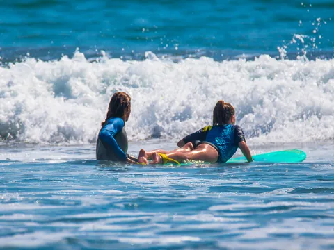 Profesor ayudando a una niña sobre su tabla de surf en el mar de Mundaka, Vizcaya