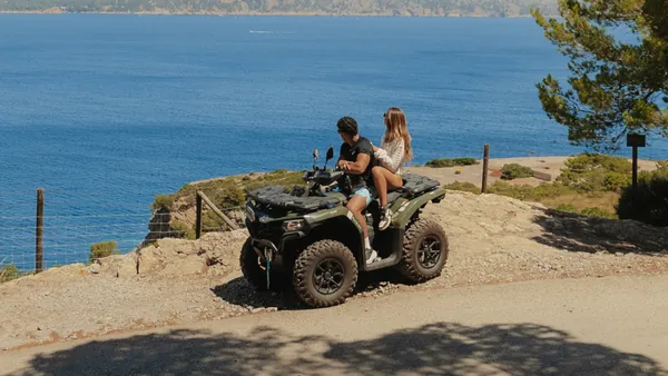 Pareja en quad parada frente al mar. contemplando el paisaje.