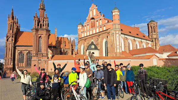 Grupo de participantes del tour en bicicleta por Vilna con la Iglesia de Santa Ana al fondo.