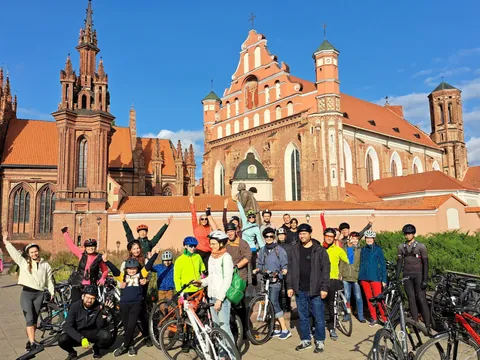 Grupo de participantes del tour en bicicleta por Vilna con la Iglesia de Santa Ana al fondo.