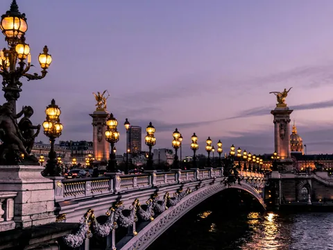 Puente Alejandro III iluminado al anochecer con el río Sena de fondo en París