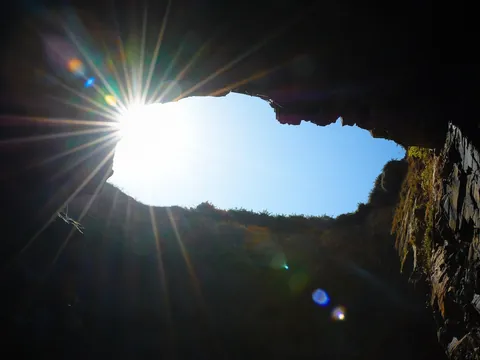 Sol filtrándose por el arco de una cueva en la Playa de las Catedrales, Galicia.