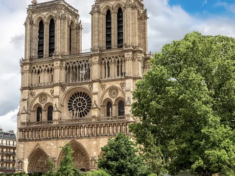 Fachada principal de la Catedral de Notre Dame en París, con dos torres góticas, gran rosetón central y tres portales ornamentados, bajo un cielo despejado.