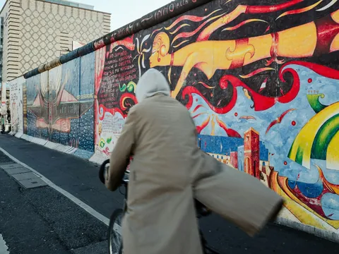 Persona en bicicleta pasando junto a los coloridos murales del Muro de Berlín en la East Side Gallery