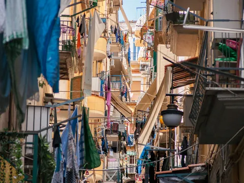 Perspectiva vertical de callejón en Barrio Español de Nápoles mostrando balcones y ropa