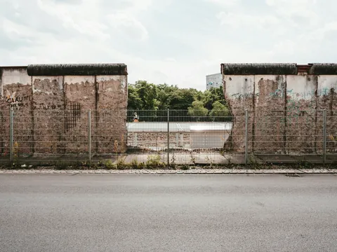Sección conservada del Muro de Berlín con una apertura y valla metálica en primer plano