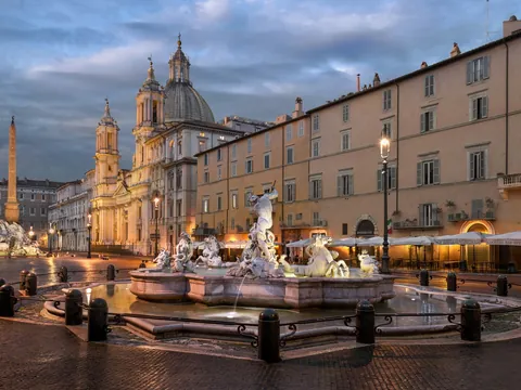 Fuente de Neptuno iluminada en la Piazza Navona de Roma al atardecer.