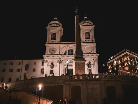 Iglesia Trinità dei Monti iluminada de noche junto al obelisco en Roma
