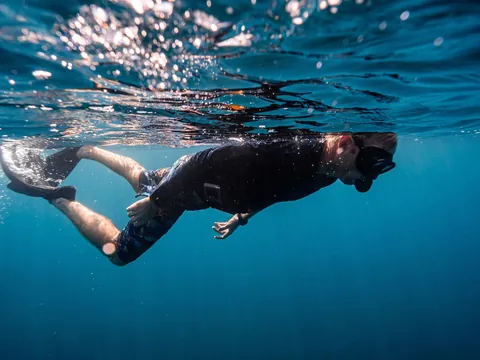 Hombre buceando bajo la superficie del mar en Menorca, Islas Baleares