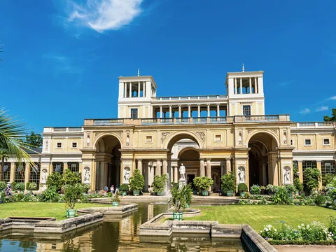 Jardines y fachada principal del Palacio de Orangerie en Potsdam bajo un cielo azul