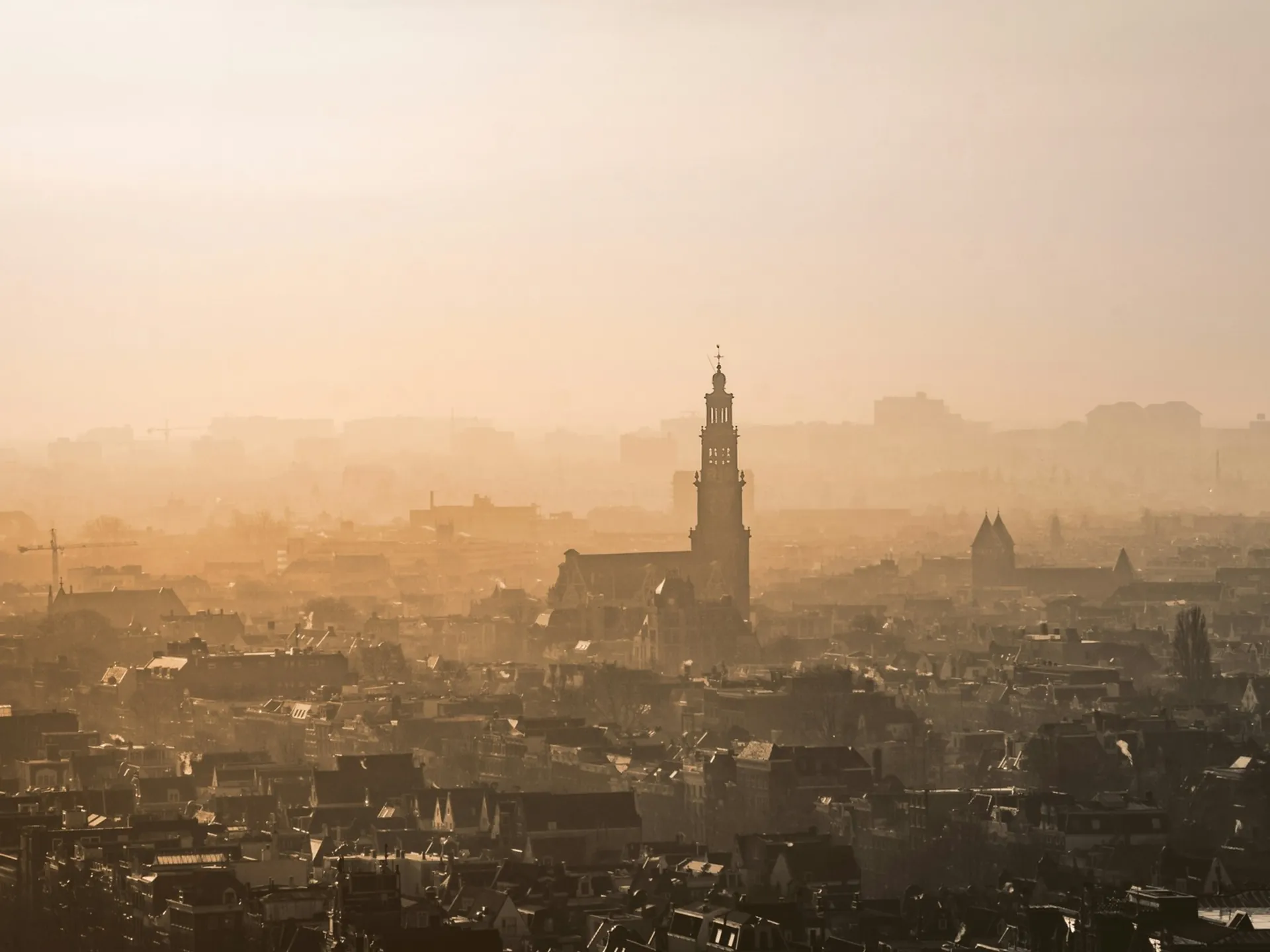 Panorámica aérea de Ámsterdam con niebla cálida y la silueta de la Westerkerk.