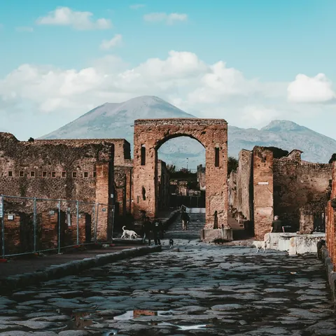 Calle empedrada con arco en las ruinas de Pompeya y el Vesubio al fondo