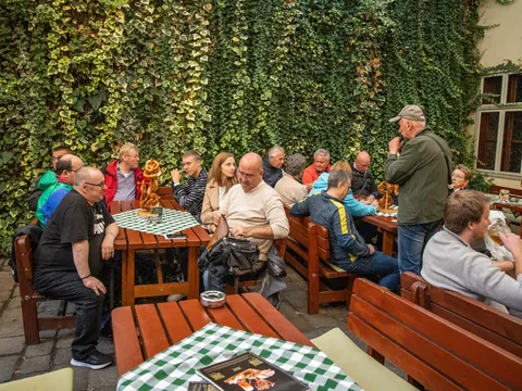 Grupo de participantes del tour de comida y bebida por Bratislava escuchan las explicaciones del guía en una cervecería local.