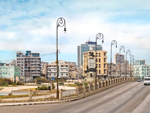 Perspectiva de la Quinta Avenida de La Habana, flanqueada por palmeras y mansiones históricas.