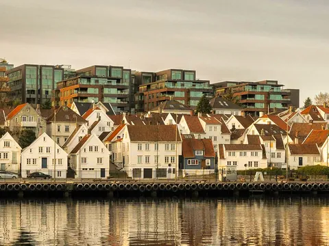 Casas tradicionales de madera en Stavanger, Noruega, frente al puerto con reflejos dorados al atardecer.