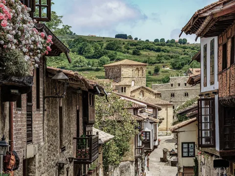 Calle con casas tradicionales y la Colegiata al fondo en Santillana del Mar