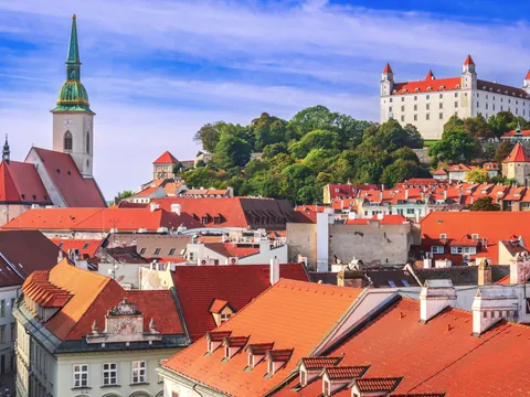 Vista panorámica de Bratislava con tejados rojos, la Catedral de San Martín a la izquierda y el Castillo de Bratislava en lo alto de una colina al fondo.