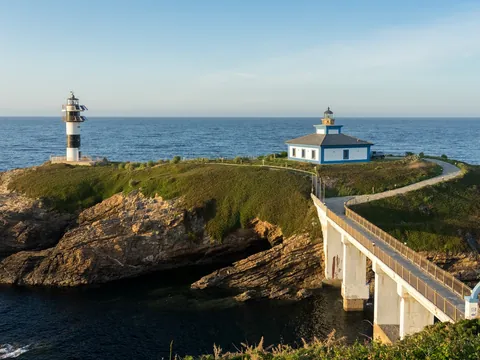 Faro de la Isla Pancha en Lugo, conectado por un puente a la costa. Edificio y torre blanca y negra junto al mar.