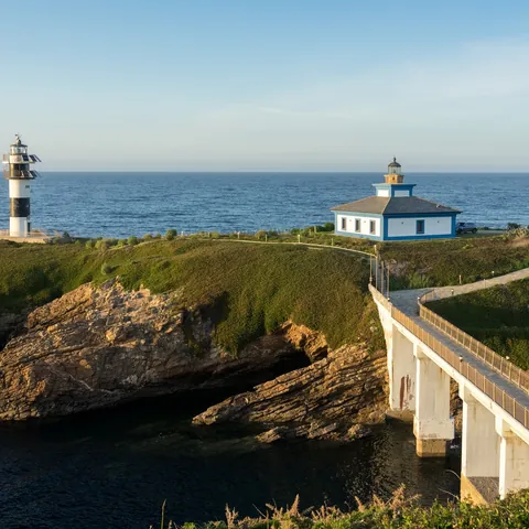Faro de la Isla Pancha en Lugo, conectado por un puente a la costa. Edificio y torre blanca y negra junto al mar.