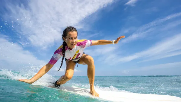 Clase de surf en Llanes, Asturias, con surfista sobre la ola