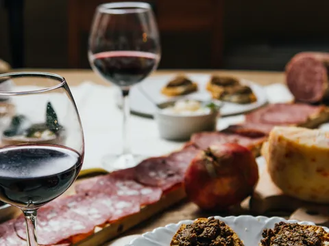 Mesa con una variedad de embutidos, quesos y copas de vino tinto de Chianti