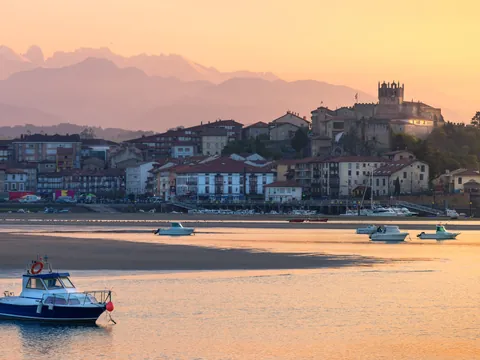 Vista de San Vicente de la Barquera al atardecer, con la iglesia y el castillo sobre el casco histórico junto a la ría.