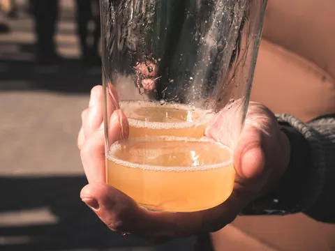 Mano sosteniendo un vaso de sidra natural escanciada en Cangas del Narcea.