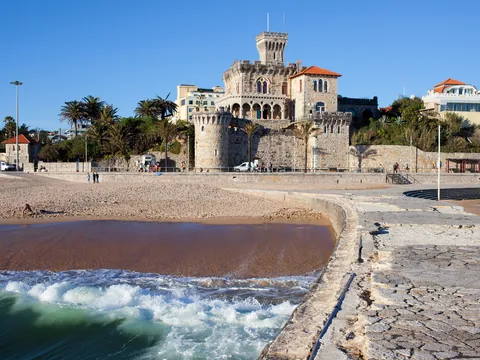Playa de Tamariz con el castillo de Estoril junto al mar en un día despejado.
