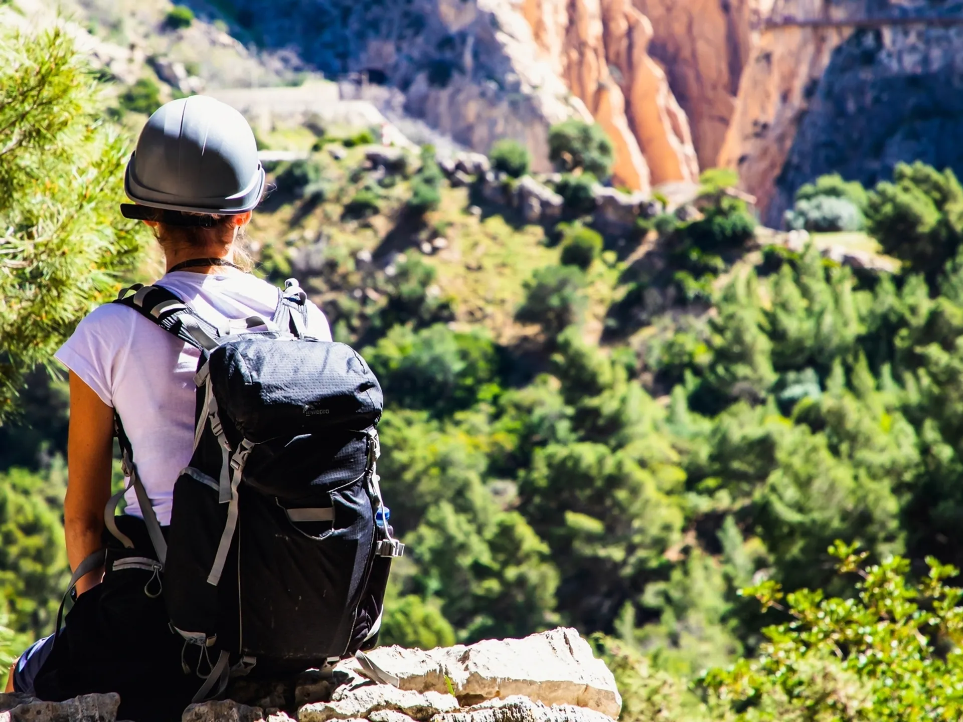 Senderista con mochila y casco contemplando el paisaje del Caminito del Rey